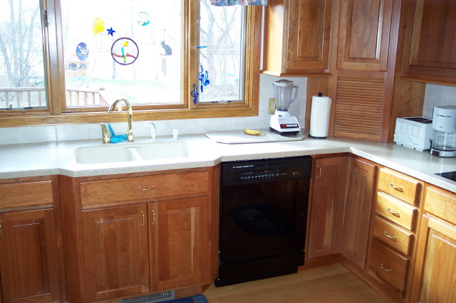 Cherry base cabinets and drawer bank beneath a solid surface counter, built by Kitchen-Works